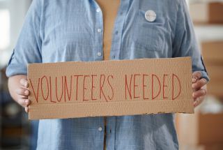 Person holding volunteer sign